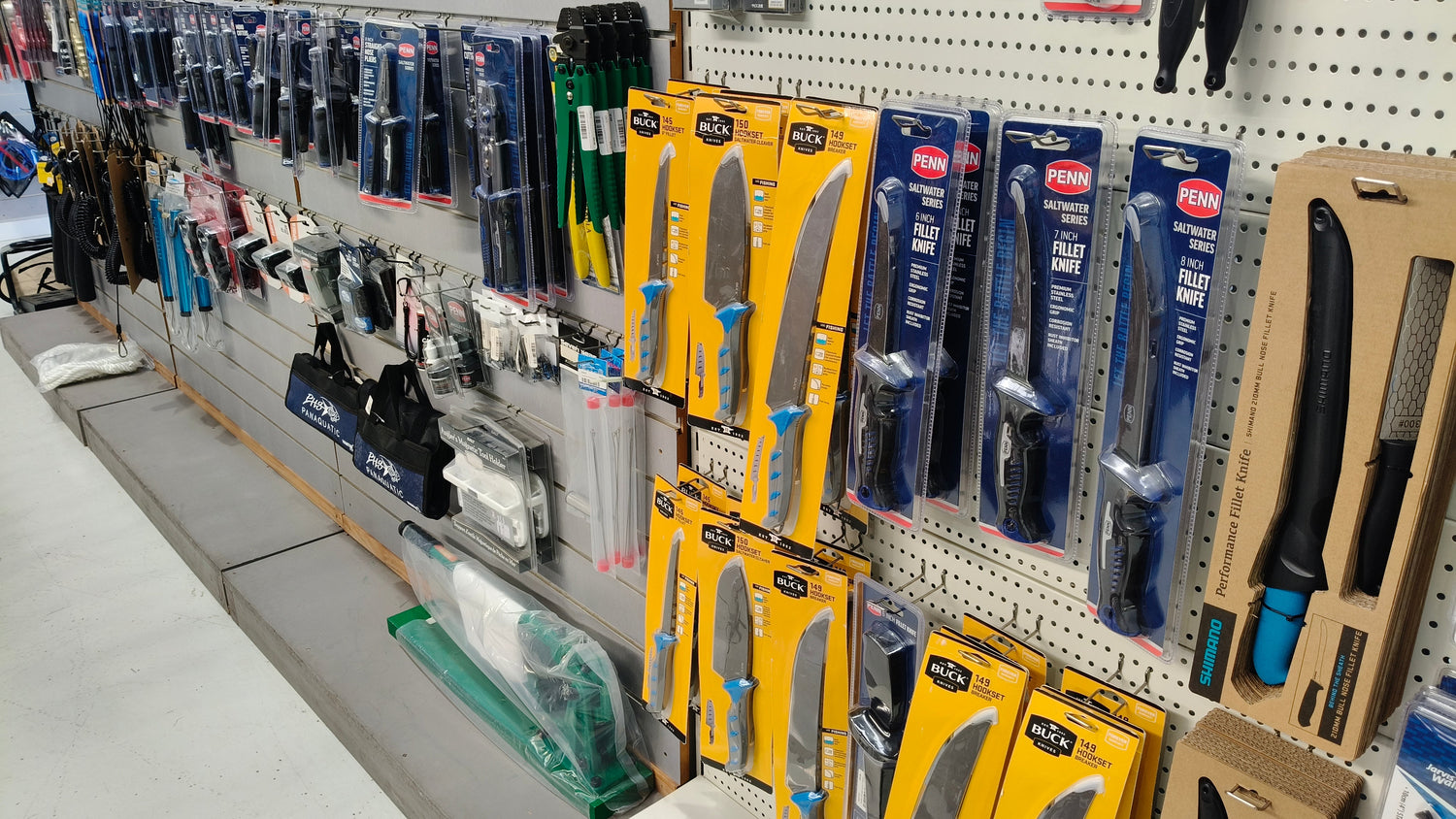Assorted fishing accessories on a pegboard display: knives, hooks, and rigging gear.