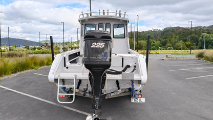 Used 2010 McLay 680 hardtop boat powered by a 225hp Mercury Optimax outboard, sitting on a tandem-axle Toko trailer. Features include boarding ladder, bait board, trim tabs, step mounts, livebait tank, twin batteries with VSR and isolation switch, GME VHF, Lowrance HDS 8, and 170L underfloor fuel tank. Warren Hay Marine, Whangarei