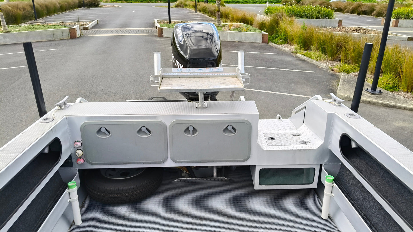 Used 2010 McLay 680 hardtop boat powered by a 225hp Mercury Optimax outboard, sitting on a tandem-axle Toko trailer. Features include boarding ladder, bait board, trim tabs, step mounts, livebait tank, twin batteries with VSR and isolation switch, GME VHF, Lowrance HDS 8, and 170L underfloor fuel tank. Warren Hay Marine, Whangarei