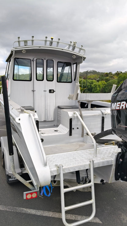 Used 2010 McLay 680 hardtop boat powered by a 225hp Mercury Optimax outboard, sitting on a tandem-axle Toko trailer. Features include boarding ladder, bait board, trim tabs, step mounts, livebait tank, twin batteries with VSR and isolation switch, GME VHF, Lowrance HDS 8, and 170L underfloor fuel tank. Warren Hay Marine, Whangarei