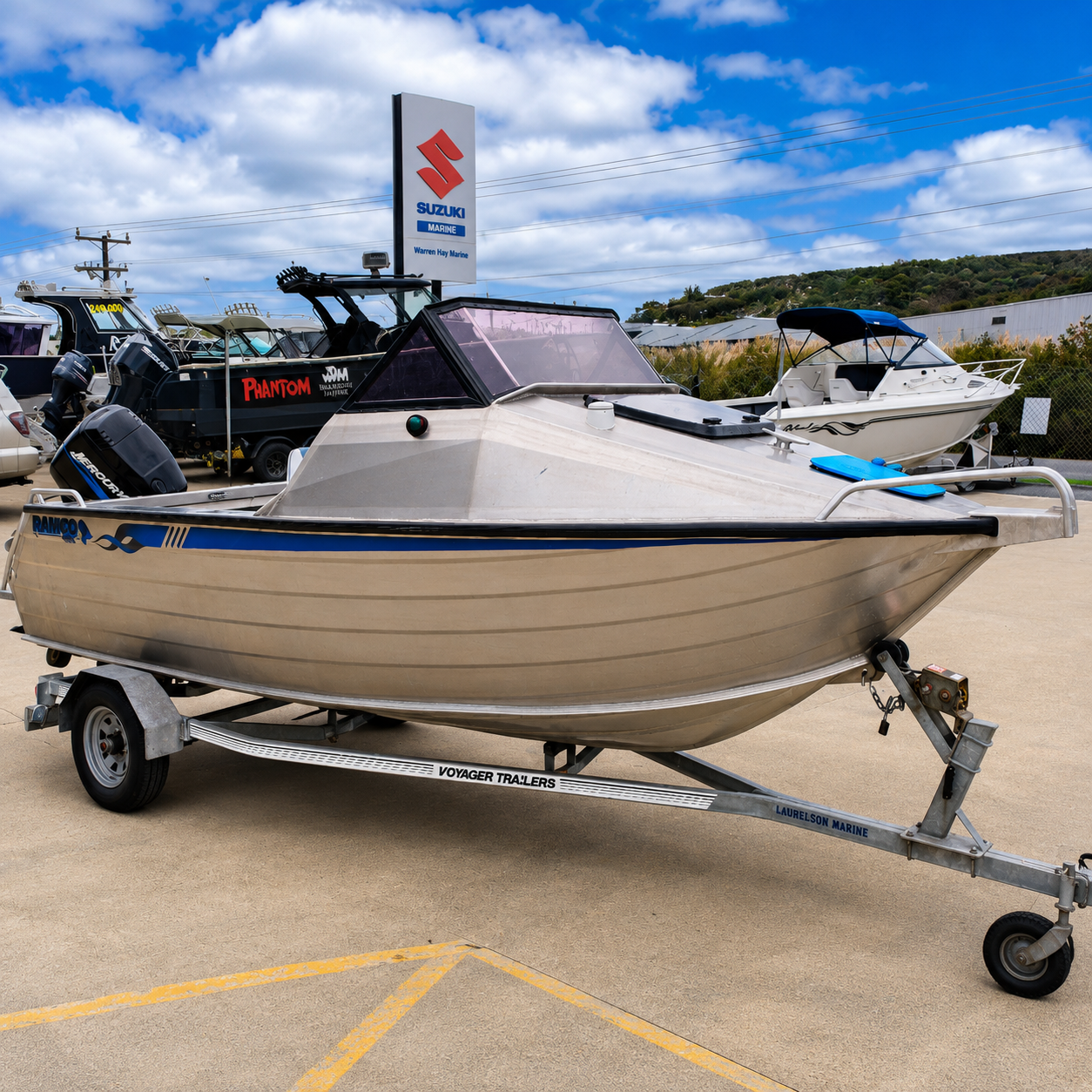 Used boats, Front starboard view of a used Ramco Getaway aluminium runabout with Mercury 90hp Saltwater outboard on a Voyager trailer, showcasing the bow, cabin, and hull design outside Warren Hay Marine, Whangārei.