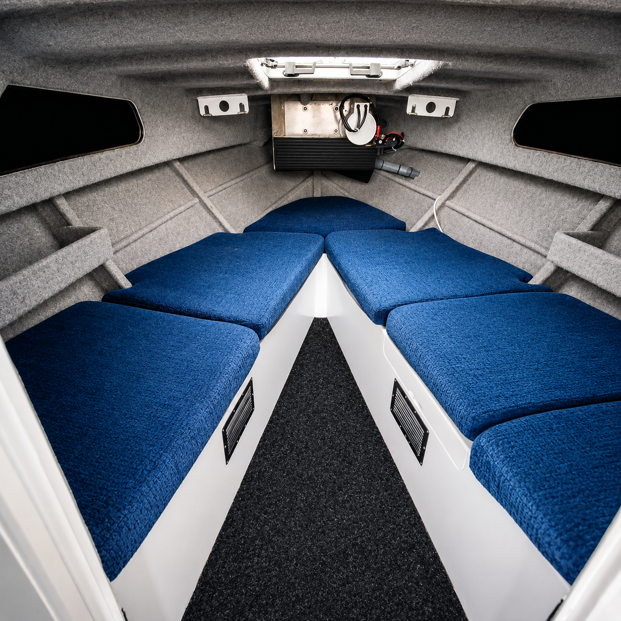 Spacious V-berth cabin inside the used Brave HT 800 hardtop, featuring upholstered bunks, carpet-lined interior, overhead hatch, and comfortable overnight accommodation.