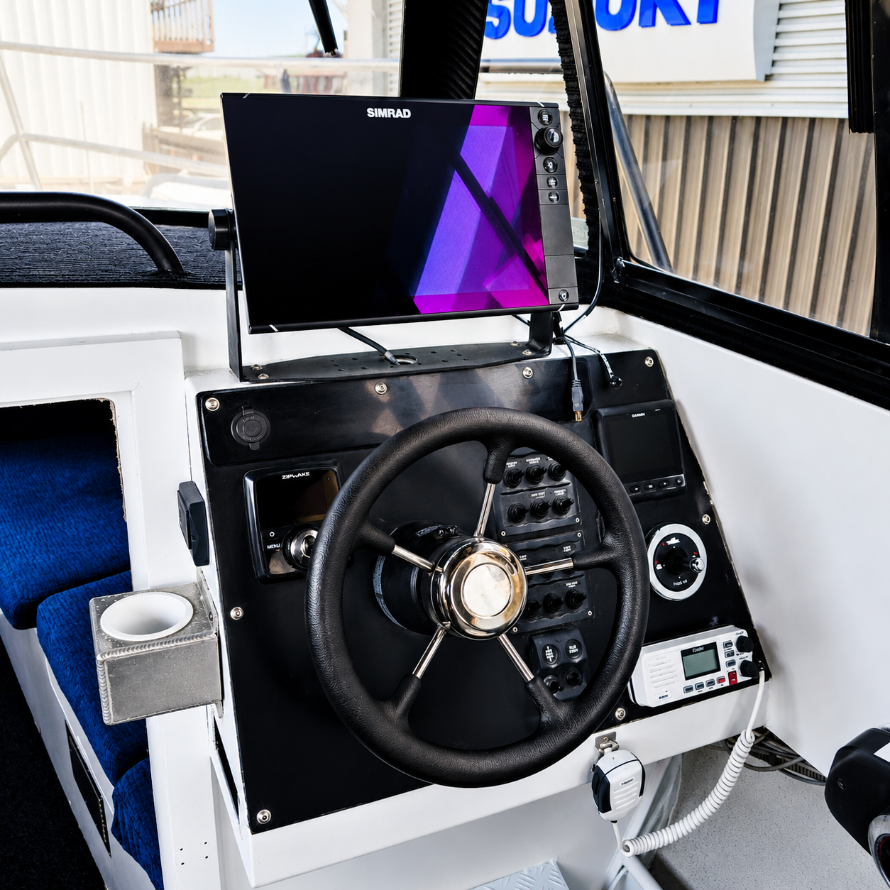 Helm station of the used Brave HT 800 hardtop featuring a Simrad NSS12 Evo2 multifunction display, Zipwake trim controller, Garmin electronics, VHF radio, and stainless steering wheel.