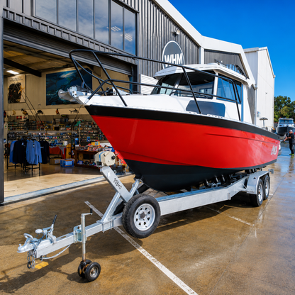 Front three-quarter view of a used Brave HT 800 aluminium hardtop boat on a galvanised tandem axle trailer, powered by a Honda BF250 outboard, photographed outside Warren Hay Marine, Whangārei