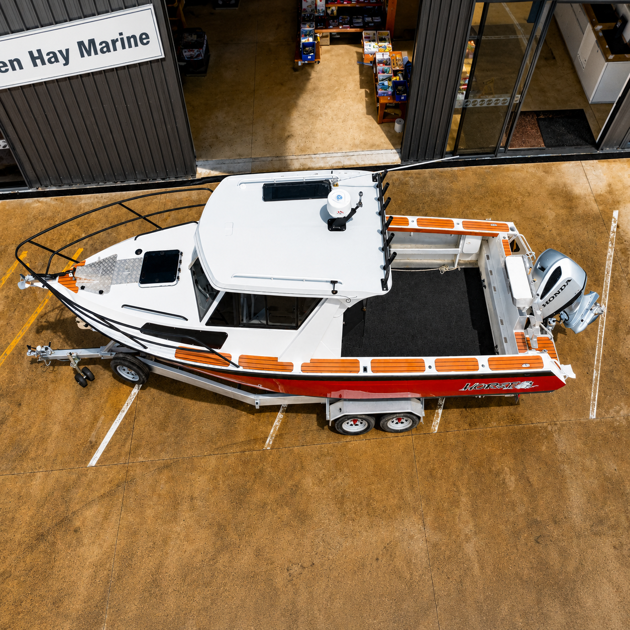 Aerial view of a used Brave HT 800 aluminium hardtop boat on a galvanised tandem axle trailer, highlighting the spacious fishing cockpit, walkaround decks, and Honda BF250 outboard.