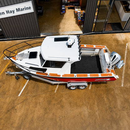 Aerial view of a used Brave HT 800 aluminium hardtop boat on a galvanised tandem axle trailer, highlighting the spacious fishing cockpit, walkaround decks, and Honda BF250 outboard.