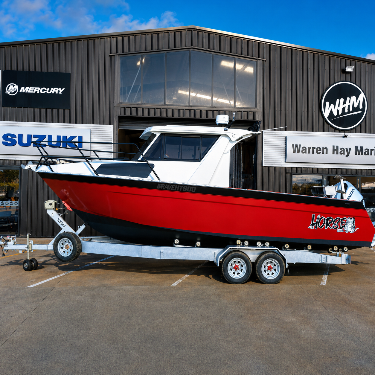 Used Brave HT 800 aluminium hardtop boat on galvanised tandem axle trailer powered by a Honda BF250 outboard, parked outside Warren Hay Marine in Whangārei