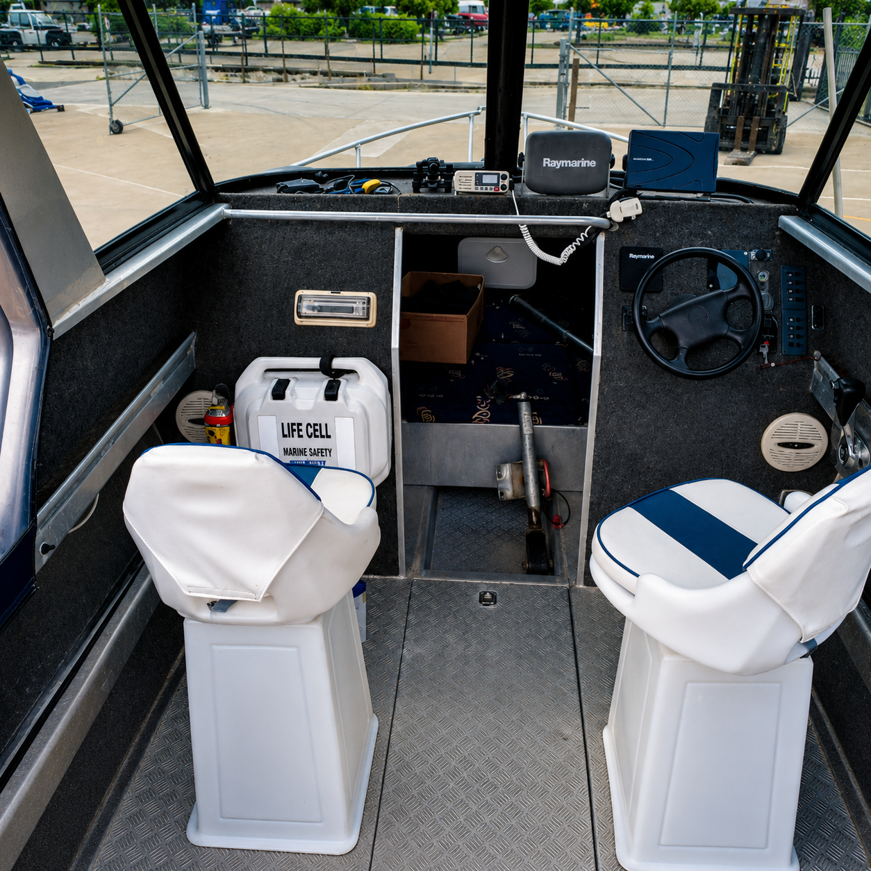 Used boats, Interior helm view of a 2018 Marco 600 Sou'Wester Hard Top showing the skipper and passenger seats, Raymarine electronics, VHF radio, helm controls, and forward cabin access. Warren Hay Marine
