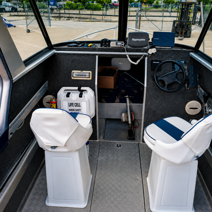 Used boats, Interior helm view of a 2018 Marco 600 Sou'Wester Hard Top showing the skipper and passenger seats, Raymarine electronics, VHF radio, helm controls, and forward cabin access. Warren Hay Marine