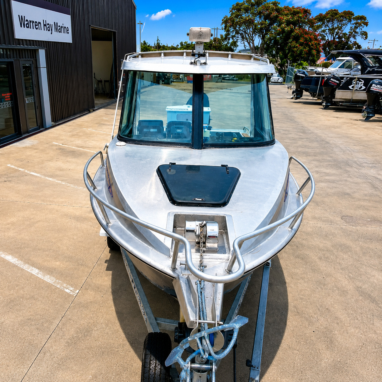 Front view of a 2018 Marco 600 Sou'Wester Hard Top with Suzuki BF140 four-stroke, featuring a Maxwell anchor winch, enclosed hardtop, and bow rails on an Ultra Trailers tandem axle trailer at Warren Hay Marine, Whangārei.